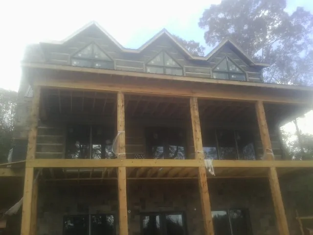Dormers and porch framing on a large log home under construction — Roof Coating work by our crew in Alder
