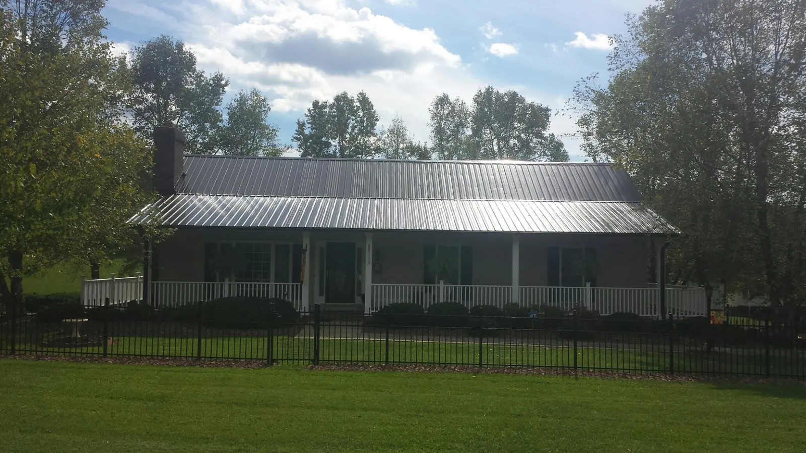 Gray metal roof on a brick ranch with a full width front porch — Gutter Guard Installation work by our crew in Alder